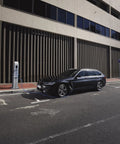 Black BMW car parked at charging station in urban setting, street view