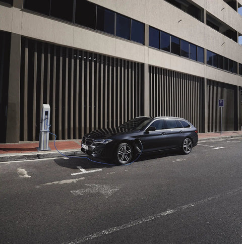 Black BMW car parked at charging station in urban setting, street view