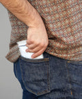 Person placing One Size Clear Hooded Disposable Rain Ponchos For Adults Bulk Pack in back pocket
