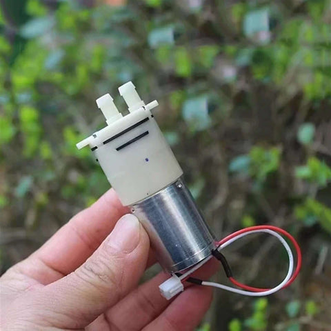 Compact DC 6V 9V 12V Micro 370 Motor Self Priming Diaphragm Water Pump held in hand, showing connectors and wiring.