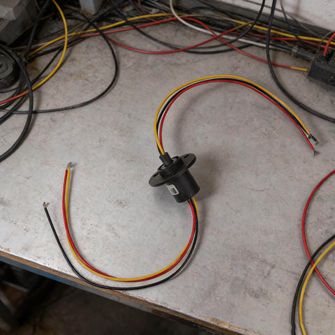High Current Slip Ring Rotating Connector With 3 Wires 10A 22Mm Diameter placed on a table with colorful wires visible