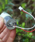 Close-up of Ultra Compact Self Priming Diaphragm Water Pump with DC 6V to 12V, 370 Micro Motor, held showing wiring detail.