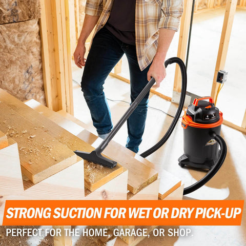 Man using Powerful 2 HP Wet Dry Vacuum With 4 Gallon Tank And Nozzles for cleanup in workshop, compact portable design, black and orange