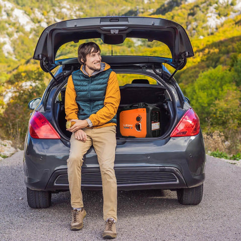 Man sitting on car trunk with 2300W Gasoline Inverter Generator With Pure Sine Wave Output, Portable Power Station visible inside.