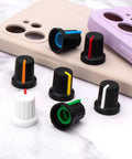 Multicolor 28 Piece 6mm Knurled Shaft Potentiometer Knob Set for Guitar Volume on table with phone cases