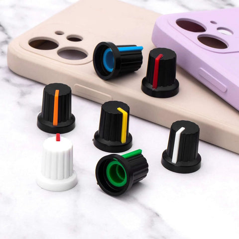 Multicolor 28 Piece 6mm Knurled Shaft Potentiometer Knob Set for Guitar Volume on table with phone cases