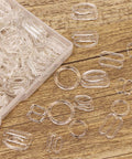 60Pcs Nylon Bra Strap Rings Hooks Set for DIY Bra and Swimwear Repair 8mm and 12mm on wooden surface with plastic case