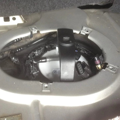Universal Gas Tank Lock Ring Tool in use for fuel pump sender removal in vehicle trunk, showing close-up of tool applied.
