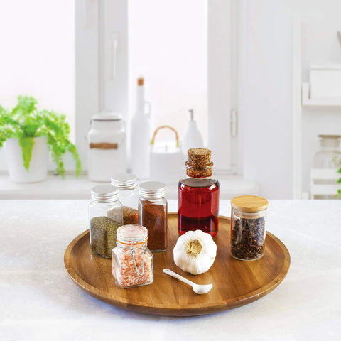 Acacia wood lazy susan organizer designed for kitchen and pantry use, featuring spices and garlic on a rotating wooden turntable.