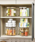 4 Pack 9.5 Inch Clear Acrylic Lazy Susan Turntable Organizer in kitchen cabinet with food items, showcasing two tiers.