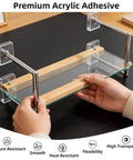 Person assembling a glass shelf with metal supports using premium acrylic adhesive on a black surface.