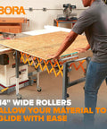 Person using Adjustable Conveyor Roller Stand with 14-inch wide rollers in woodworking shop, smoothing plywood movement.