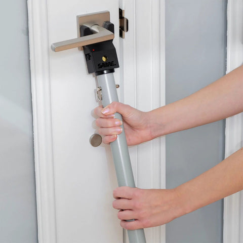 Person installing Adjustable Door Security Bar With Vibration Detecting Alarm And 115 Decibel Siren That Emits Up To 1100 Feet