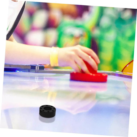 Air hockey table with player using a red paddle, black bumper shown on the table surface