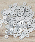 Pile of aluminum back up rivet washers for three sixteenth inch rivets, pack of 300, on wooden surface.