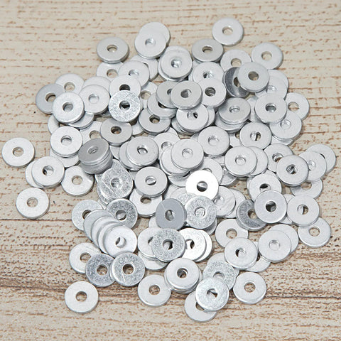 Pile of aluminum back up rivet washers for three sixteenth inch rivets, pack of 300, on wooden surface.