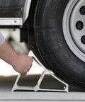 Heavy Duty Aluminum Wheel Chock For Trucks And Semis With Ribbed Slope For Maximum Grip And Secure Parking On Snow And Ice 6 X 8.75 X 5.86 Inch By Buyers Products being positioned under a truck tire for secure parking.