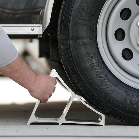 Heavy Duty Aluminum Wheel Chock For Trucks And Semis With Ribbed Slope For Maximum Grip And Secure Parking On Snow And Ice 6 X 8.75 X 5.86 Inch By Buyers Products being positioned under a truck tire for secure parking.