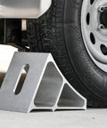 Heavy Duty Aluminum Wheel Chock For Trucks And Semis With Ribbed Slope For Maximum Grip And Secure Parking On Snow And Ice 6 X 8.75 X 5.86 Inch By Buyers Products positioned under a truck tire.