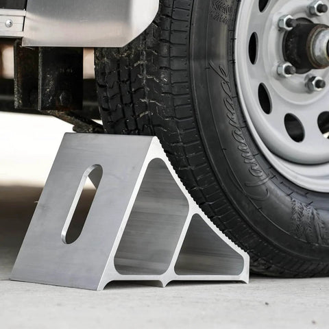 Heavy Duty Aluminum Wheel Chock For Trucks And Semis With Ribbed Slope For Maximum Grip And Secure Parking On Snow And Ice 6 X 8.75 X 5.86 Inch By Buyers Products positioned under a truck tire.