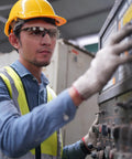 Worker in hard hat wearing ANSI Z87 Plus Impact Resistant Polycarbonate Safety Glasses Black Frame Pack 12 operating machinery.