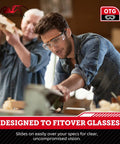 Man wearing ANSI Z87.1 Safety Glasses For Over Eyeglasses With Anti Scratch Lenses, in workshop environment, focused on a task.