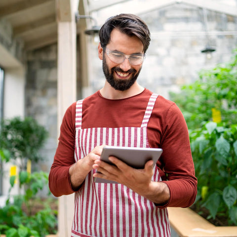 Man wearing ANSI Z87 Safety Glasses With Impact-Resistant Lenses And UV Protection holding a tablet in a greenhouse
