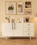 White sideboard with drawers featuring antique brass cabinet knobs, wall art above, modern wooden floor, home decor setting.