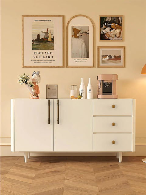 White sideboard with drawers featuring antique brass cabinet knobs, wall art above, modern wooden floor, home decor setting.