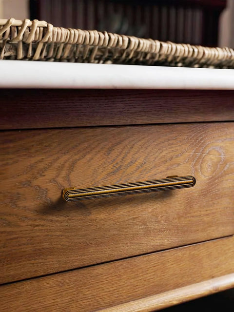 Close-up of installed 3-inch antique brass cabinet pull on a wooden drawer, part of the 10 Pack Antique Brass Cabinet Pulls 3 Inch 76mm.