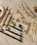 Variety of zinc alloy cabinet pulls in antique brass, black, and gold finishes on stone surface, featuring different designs and sizes.