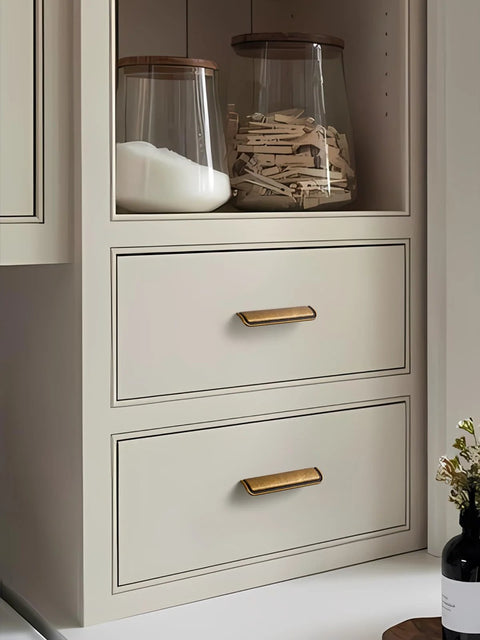 Five Pack 5 Inch Antique Brass Cabinet Cup Pulls For Kitchen And Bath installed on white drawers, 128mm length.