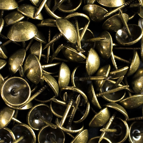 Close-up of antique brass upholstery tacks, 100 pcs per box, with 7/16 inch head and 1/2 inch shank for securing fabric and trim.