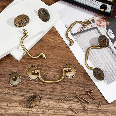 Vintage Bail Pull Handles Set Of 4 Antique Bronze Alloy Drop Pulls on wooden surface with screws, ideal for cabinets and dressers.