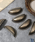 Brass Bronze Cup Drawer Pulls Set Twelve Pack Cabinet Cup Pulls arranged on a table with screws, 3 inch spacing.