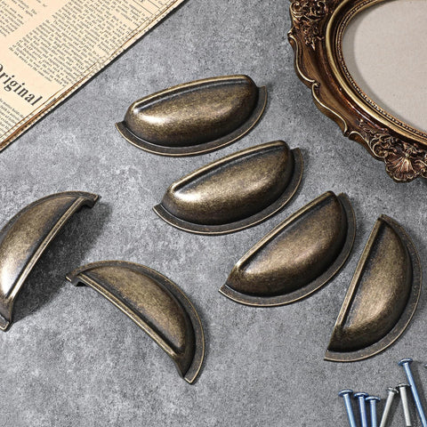 Brass Bronze Cup Drawer Pulls Set Twelve Pack Cabinet Cup Pulls arranged on a table with screws, 3 inch spacing.