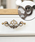 Front view of 4 pack 3.25 inch center to center antique bronze bail drawer pulls on white dresser with close-up detail.
