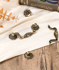 Antique Bronze Drawer Pulls Set With Screws Rustic Vintage Drop Handles on white fabric, showing decorative details, perfect for cabinets and furniture