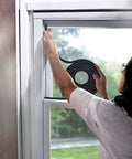 Person applying Self-Stick Rubber Foam Weatherseal, 3/8"W, 3/16"T, Black to window frame to prevent drafts.