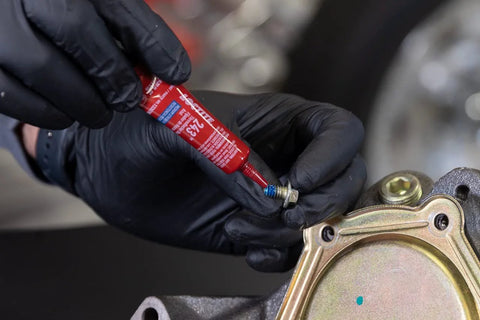 Applying Blue 243 Oil-Resistant Threadlocker to metal fastener for automotive use, demonstrating medium-strength adhesion and oil resistance.