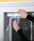 Applying the Indoor Shrink Window Kit for Large Windows and Patio Doors, 84 Inch By 110 Inch Clear Film on a window frame.