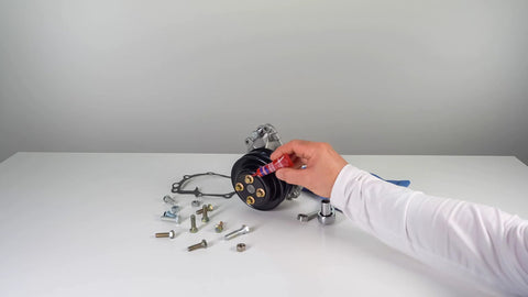 Person applying Permanent Thread Lock And Seal For Nuts Bolts And Fasteners High Strength Red 271 to engine bolts on a white surface