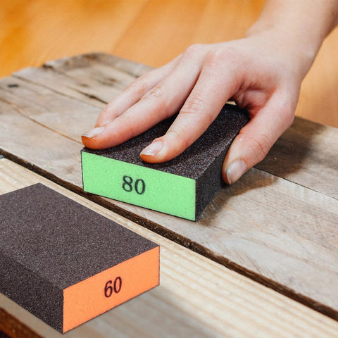 Hand using Assorted Grit Sanding Block Set 60 80 120 220 Blocks For Wood Drywall Metal on wooden surface