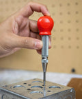 Hand holding 5-Inch Automatic Center Punch for Metal and Other Materials, demonstrating precision marking on metal surface.