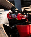 Pouring Shift Restore Automatic Transmission Additive 16 Oz Bottle into car engine with red funnel for smoother shifts