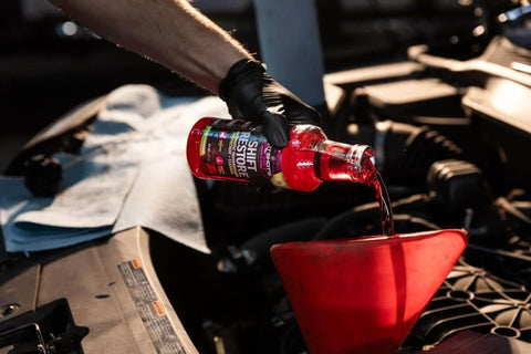 Pouring Shift Restore Automatic Transmission Additive 16 Oz Bottle into car engine with red funnel for smoother shifts