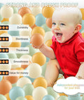 Baby in a red shirt sitting with Ball Pit Balls (100 Pack, Orange,Teal) Plastic Balls for Various Games, Ideal for Ball Pits and Playhouses.