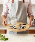 Person holding 11 Inch Bamboo Lazy Susan Turntable Organizer with Gold Handle for tabletop use, featuring food and drink setup.
