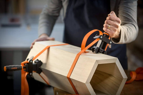 Adjustable Clamp Pony 1225 Rapid Acting Band Clamp With Non Marring 1x1 Inch Jaws securing an irregular wooden shape