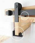 Close-up of 8.2 FT Heavy Duty Sturdy Sliding Barn Door Hardware Kit, Black, showing door rollers and floor guide on wooden panel